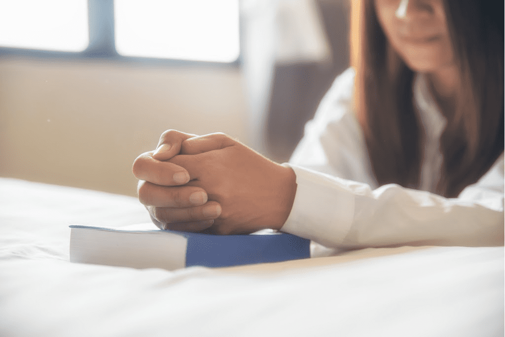 woman praying on the bed