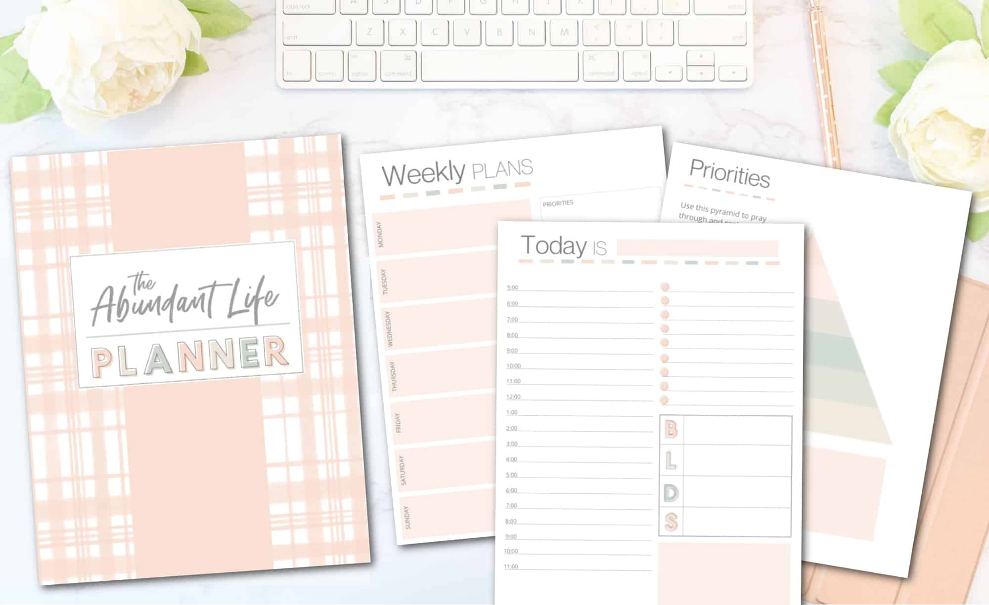 The Abundant Life Planner pages on a desk with a computer and flowers