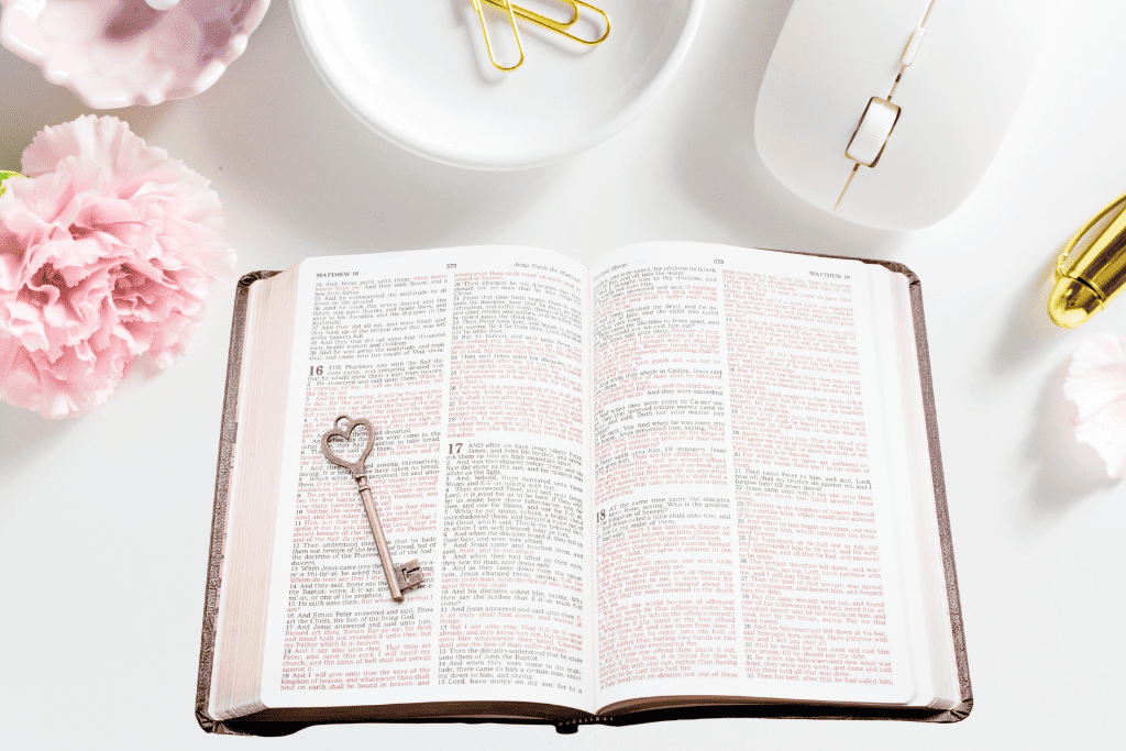 open Bible on styled desk with pretty pink flowers and gold desk accessories