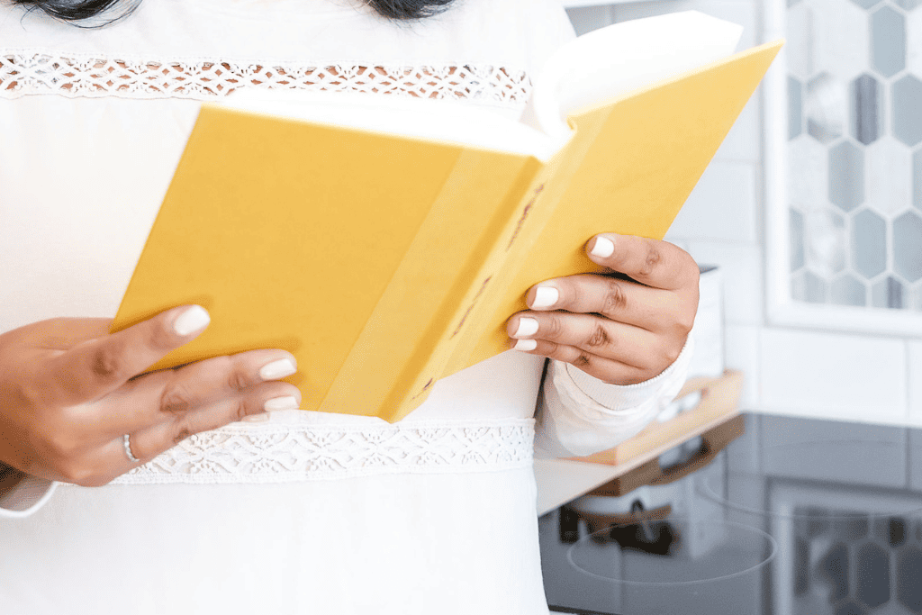 woman reading a yellow book in a white shirt